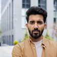 Close-up portrait of young Indian man, serious man concentrating and thoughtfully looking at camera