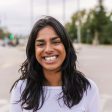 Happy young indian woman smiling at camera standing at city street