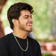 Smiling young indian man portrait in black t shirt and silver neck chain outdoor green public park